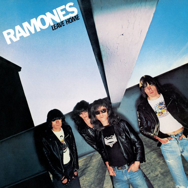 Die Ramones stehen in Lederjacken vor einer modernen Architektur mit blauem Himmel.