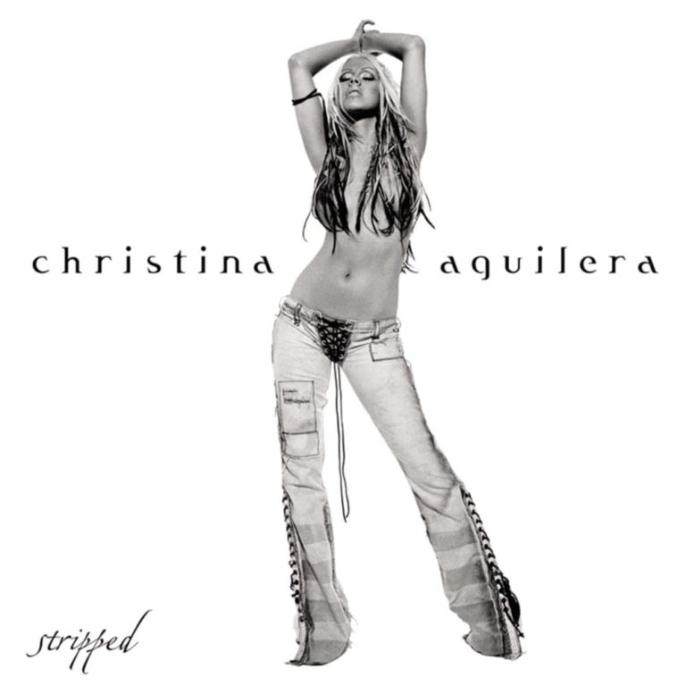 Christina Aguilera posiert in Jeans vor weißem Hintergrund mit Albumtitel Stripped.