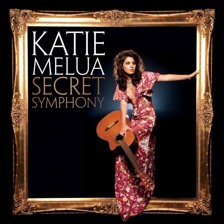Katie Melua in floralem Kleid mit Gitarre in goldenem Rahmen