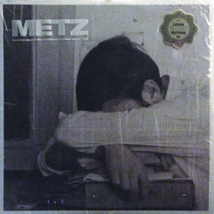 Schwarz-weißes Cover mit einem Kind, das den Kopf auf verschränkte Arme legt, daneben ein goldener Aufkleber.
