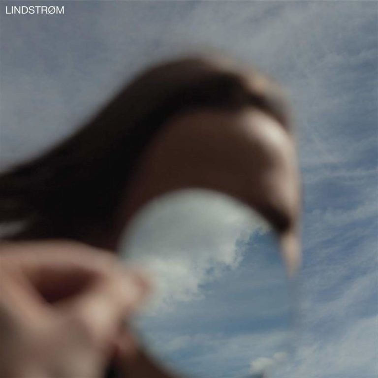 Verschwommene Person hält Spiegel, der den Himmel reflektiert.