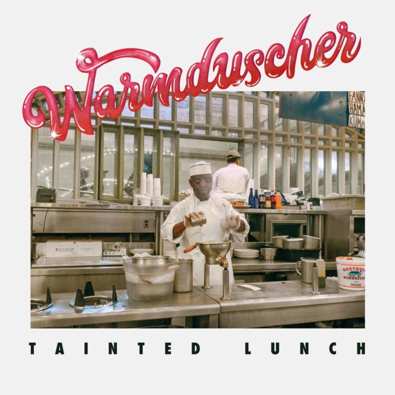 Koch in einer industriellen Küche mit Dampf und Küchenutensilien, umgeben von Edelstahlgeräten.