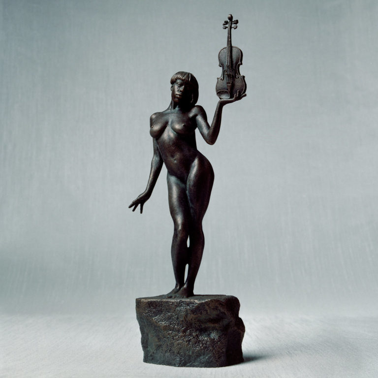 Bronzestatue einer Frau mit erhobener Geige auf einem Sockel vor grauem Hintergrund
