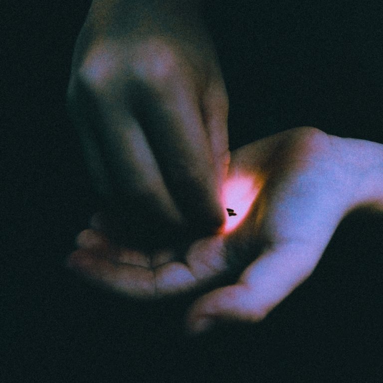 Nahaufnahme einer Hand, die ein kleines glühendes Objekt hält.