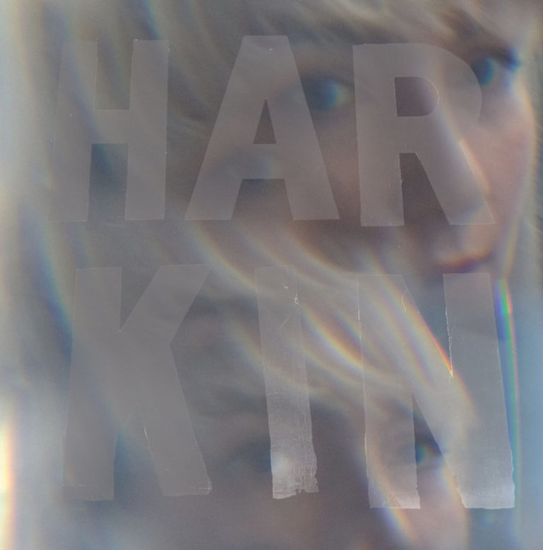 Nahaufnahme eines Gesichts mit dem Schriftzug HARKIN in großen Buchstaben überlagert.