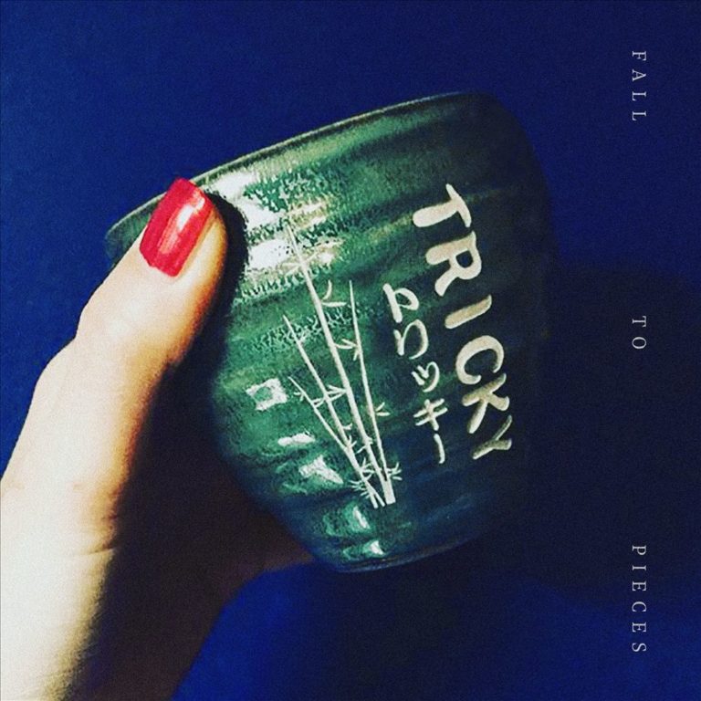 Hand mit rotem Nagellack hält eine grüne Tasse mit der Aufschrift Tricky.