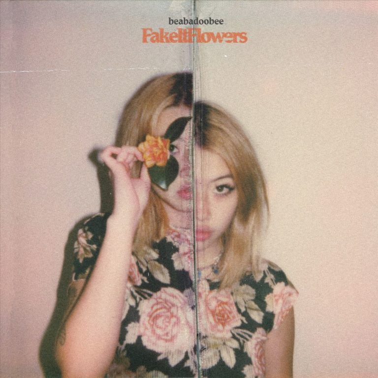 Frau mit Blume vor dem Gesicht, trägt geblümtes Kleid, Cover von Fake It Flowers.