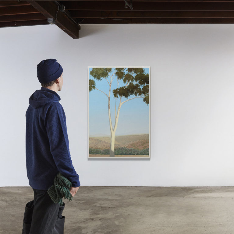 Person betrachtet ein großes Gemälde eines Baumes in einer Galerie.