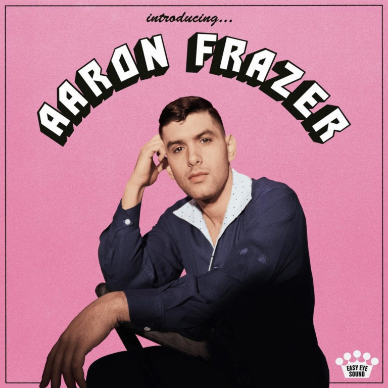 Albumcover von Aaron Frazer – Introducing: Porträt des Sängers im Retro-Stil vor rosa Hintergrund, sitzend mit nachdenklichem Blick, schwarzer Rahmen und geschwungener Schrift.