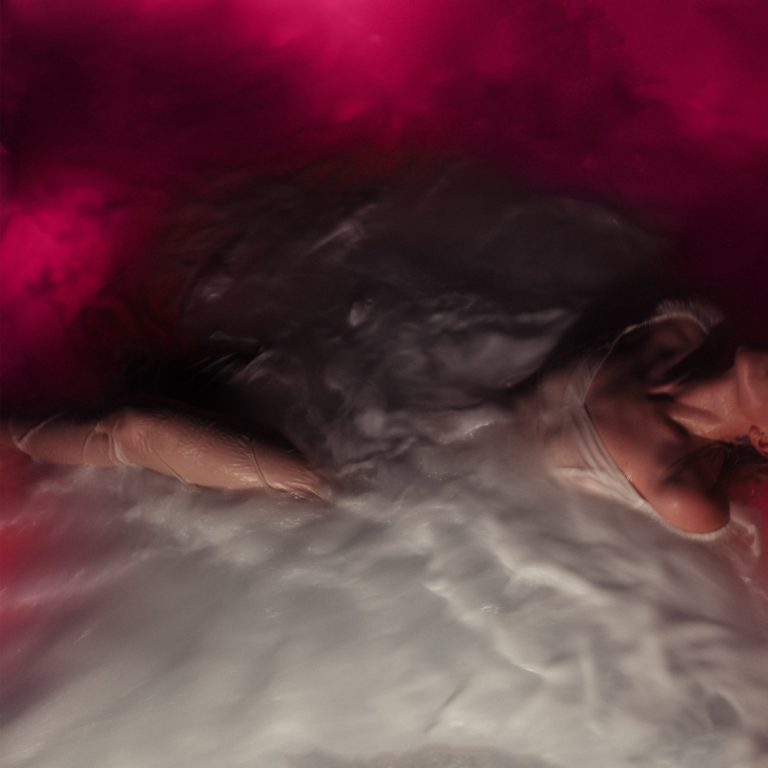 Albumcover von FLOWERS for VASES zeigt eine verschwommene Frauengestalt halb untergetaucht in weißem Wasser, umgeben von rosa Dunst – intim, verletzlich und traumgleich inszeniert.