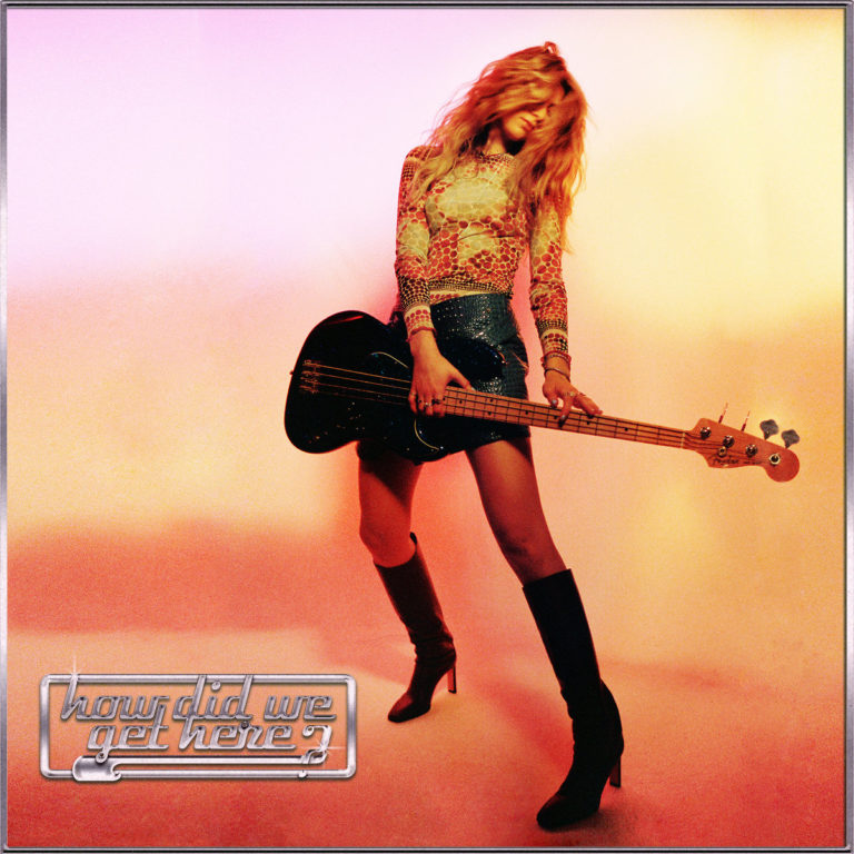 Cover des Debütalbums How Did We Get Here? von Blu DeTiger: Die Musikerin steht lasziv in buntem Licht mit einem schwarzen E-Bass, umgeben von rosa-orangefarbenem Farbverlauf. Ihr Outfit aus Netzoberteil, Minirock und kniehohen Stiefeln kombiniert Retro-Glamour mit modernem Pop-Appeal. Unten links ist der Albumtitel im silbernen Chrome-Schriftzug platziert.