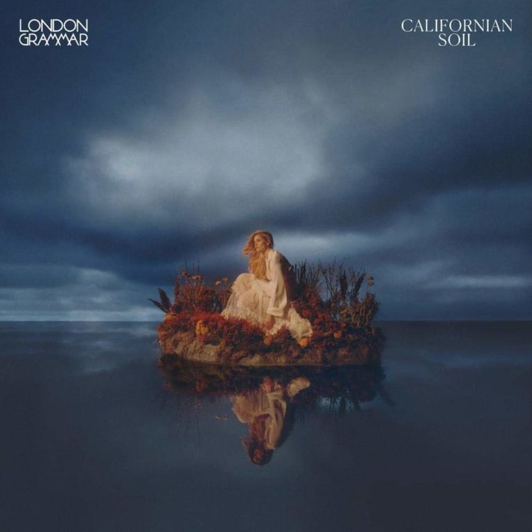 Eine Frau in cremefarbener Kleidung sitzt auf einem mit Blumen geschmückten Floß, das still auf spiegelglattem Wasser treibt, unter einem dramatisch bewölkten Himmel – Albumcover von London Grammar.