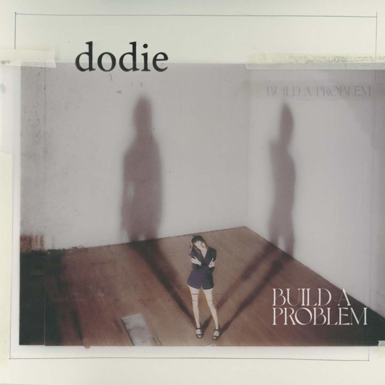 Das Cover zeigt Dodie in einem leeren Raum mit Holzfußboden, schüchtern in der Ecke stehend. Zwei übergroße Schatten an den Wänden symbolisieren emotionale Last oder innere Konflikte. Oben steht „dodie“, unten rechts der Albumtitel „Build A Problem“.