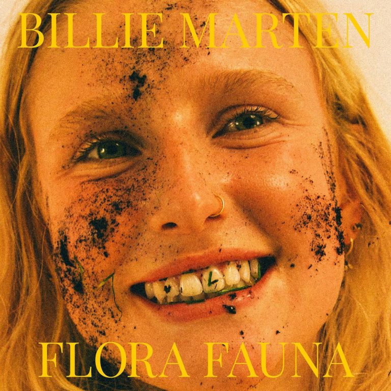 Albumcover von Billie Marten – „Flora Fauna“: Ein lächelndes Gesicht mit Erde im Gesicht und auf den Zähnen, in Nahaufnahme, mit gelbem Schriftzug.