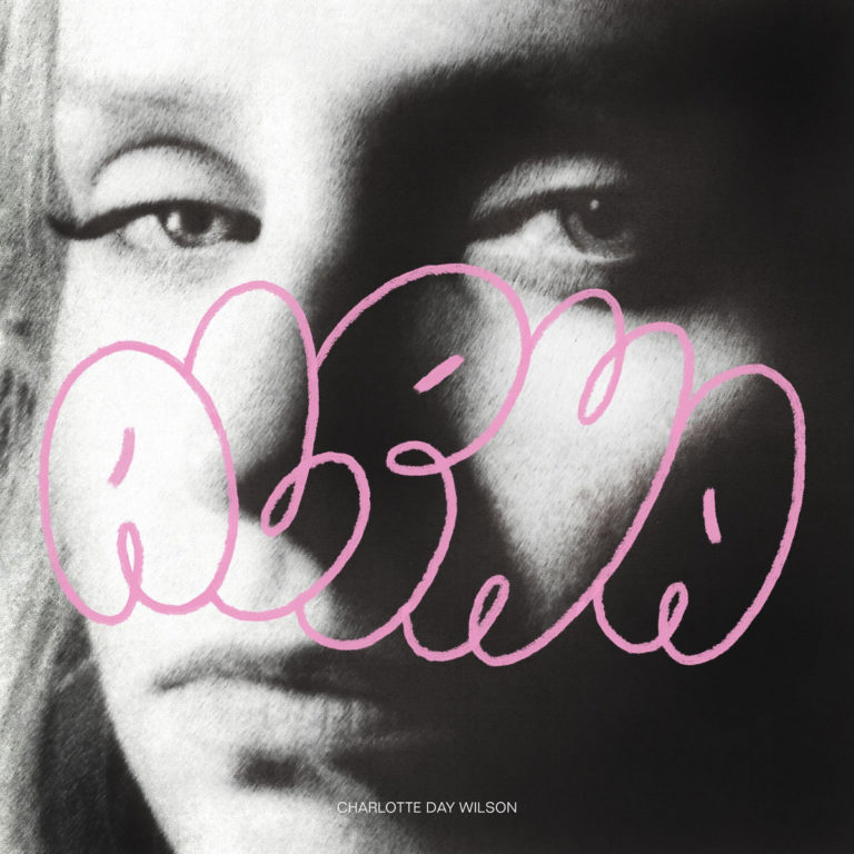 Albumcover von Charlotte Day Wilsons Alpha: Unscharfes Schwarz-Weiß-Porträt mit großem rosa Graffiti-Schriftzug und subtiler Melancholie im Blick.
