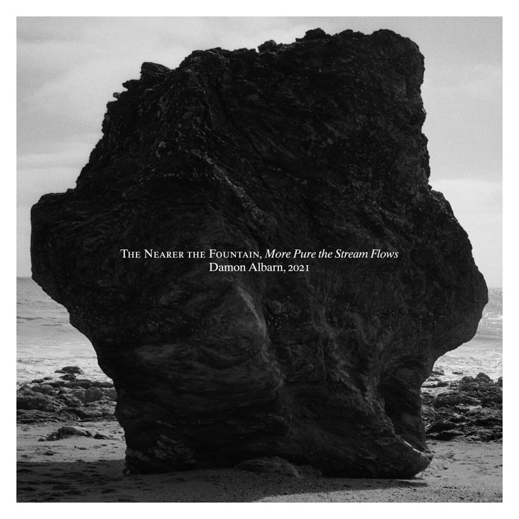 Schwarz-weiß-Foto eines massiven Felsens am Meer – still, schwer und einsam, mit Titeltext des Damon-Albarn-Albums auf der Oberfläche.