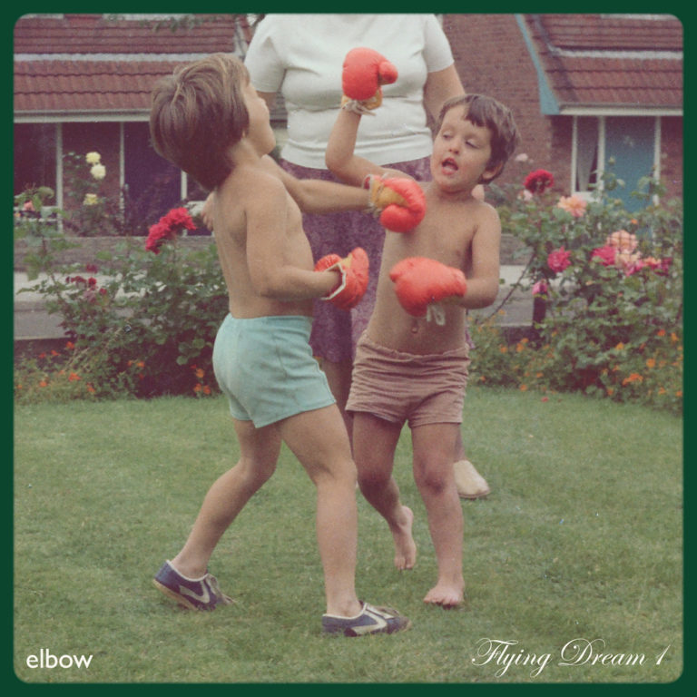 Zwei Kinder boxen lachend mit roten Handschuhen im Garten, während eine erwachsene Figur im Hintergrund steht – eine Szene voller Nostalgie und Zärtlichkeit.