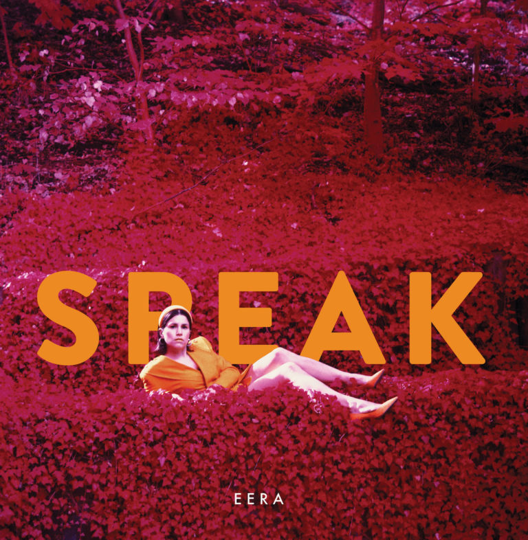 Künstlerin in orangefarbenem Outfit liegt auf leuchtend purpurrotem Laubteppich im Wald, darüber der Albumtitel „SPEAK“ in großen orangen Buchstaben.