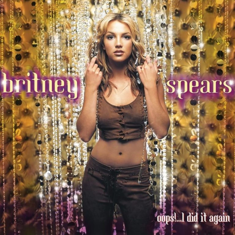 Britney Spears steht vor einem funkelnden Hintergrund aus Perlen und Blumen.