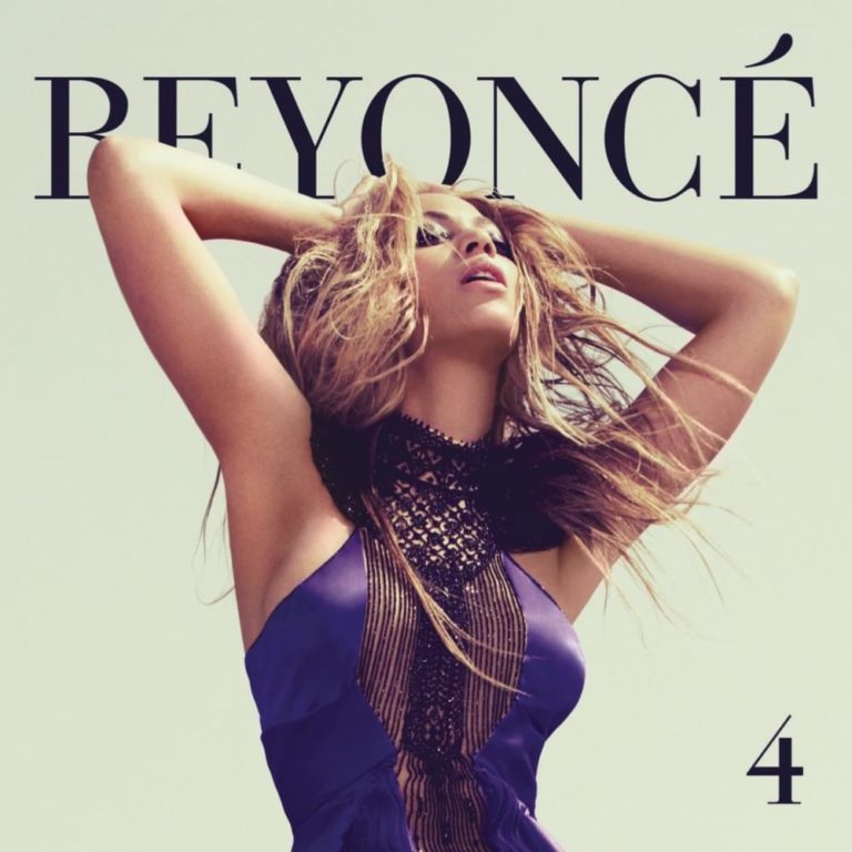 Beyoncé in lila Kleid mit hochgesteckten Armen vor hellem Hintergrund.