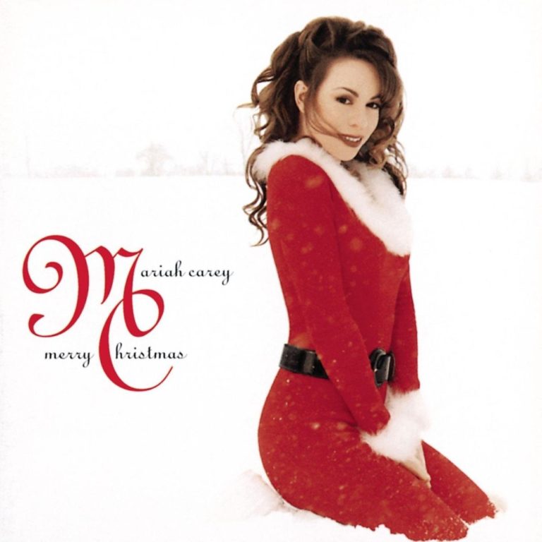 Mariah Carey kniet im Schnee in einem roten Weihnachtskostüm mit weißem Pelzbesatz.