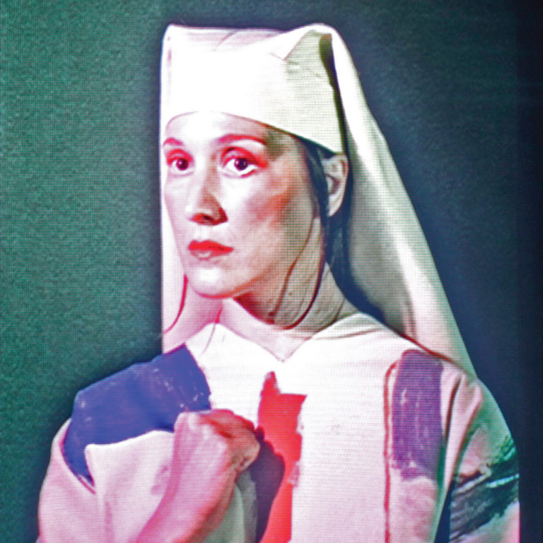 Cate Le Bon im Nonnenkostüm mit ernstem Blick, Standbild-Ästhetik und rosarotem Lichtschein – Cover ihres Albums „Pompeii“, das visuell zwischen Sakralität und Popironie schwebt