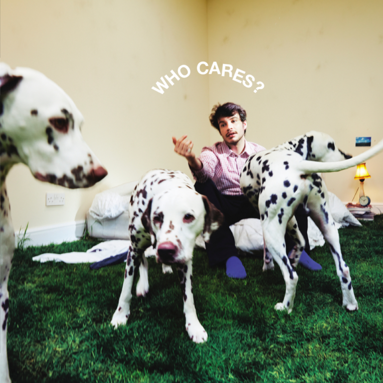 Rex Orange County sitzt entspannt auf Kunstrasen in einem leeren Raum, umgeben von drei Dalmatinern, über ihm steht in weißen Buchstaben: „WHO CARES?“.