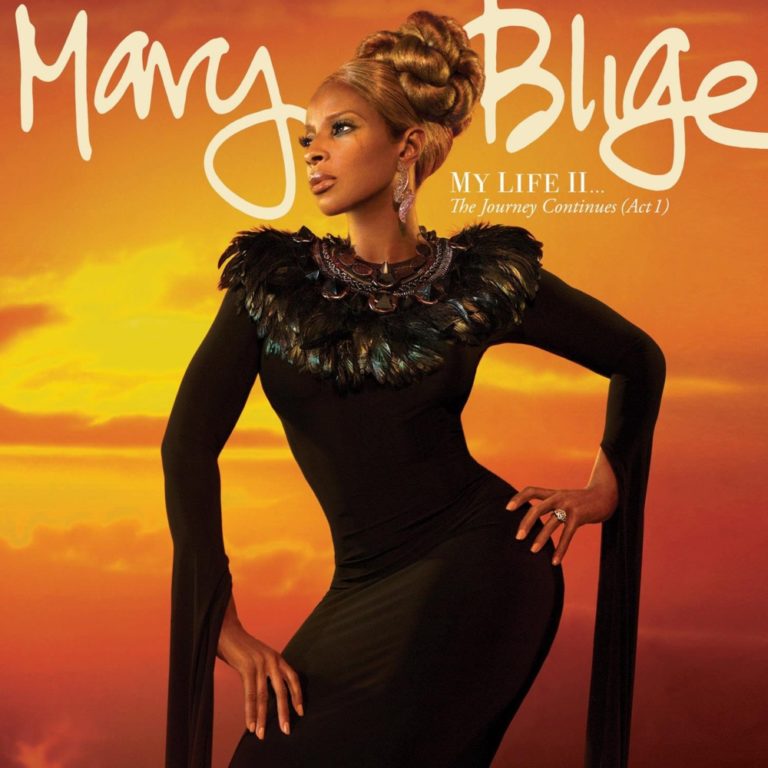 Mary J. Blige in elegantem schwarzen Kleid vor orangefarbenem Himmel.