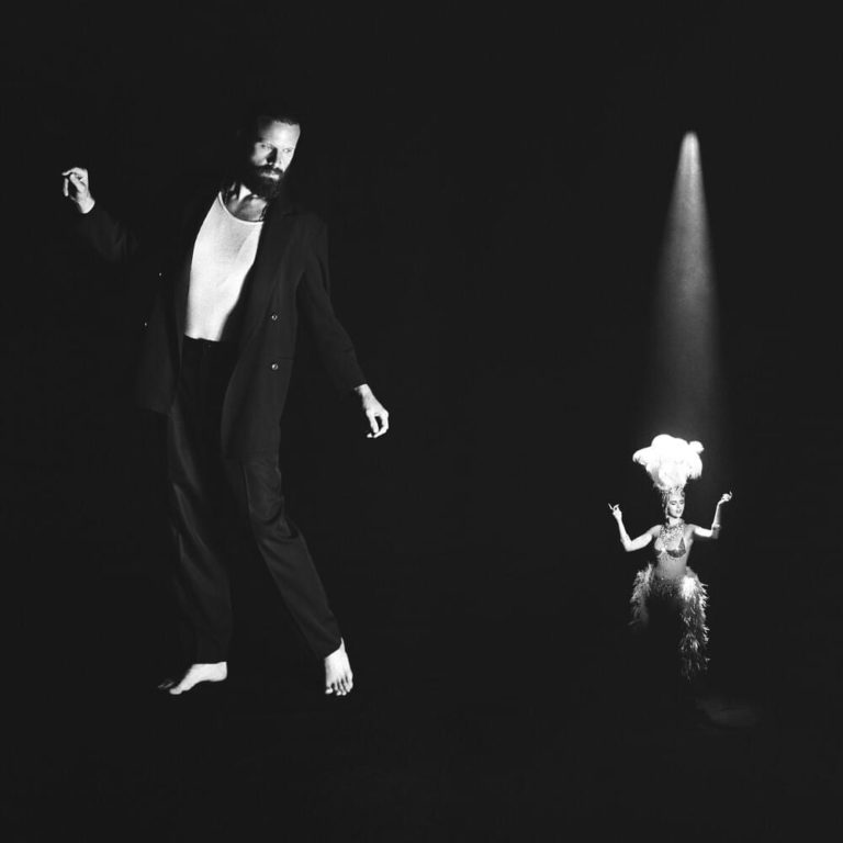Schwarz-weißes Bühnenbild: Father John Misty in elegantem Anzug tanzt unter einem Scheinwerfer, während ein kleiner Revue-Tänzer im Spotlight neben ihm steht – Cover von „Chloë and the Next 20th Century“.