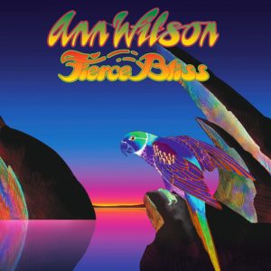 Ein bunt schillernder Papagei sitzt auf einem Felsen vor einem knallbunten Sonnenuntergang, darüber der Schriftzug „Ann Wilson – Fierce Bliss“.