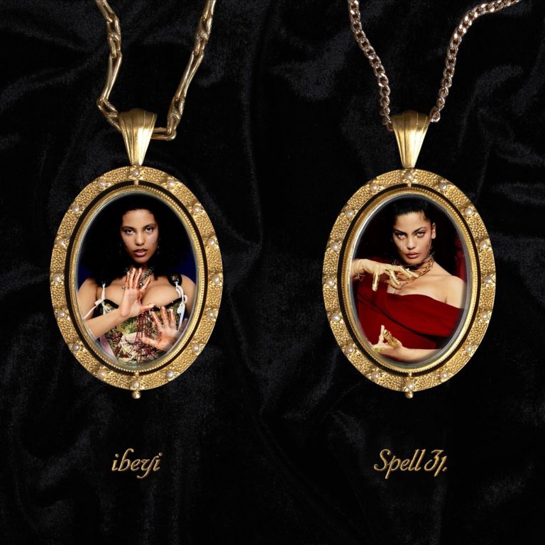 Zwei goldene Medaillon-Anhänger auf schwarzem Samt, die Lina und Naomi Diaz von Ibeyi mit vergoldeten Händen in teils klassischer, teils elektronischer Pose zeigen – Cover zu „Spell 31“.