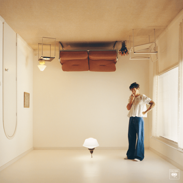 Ein heller, fast minimalistisch eingerichteter Raum mit weißen Wänden und Boden. Eine Person mit kurzem Haar und weitem blauen Outfit steht entspannt am Fenster, während eine moderne Lampe auf dem Boden leuchtet. Die Atmosphäre ist ruhig und offen.