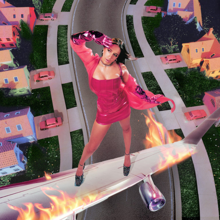 „Tate McRae steht in auffälligem Pink-Outfit auf einem brennenden Flugzeugflügel, während darunter eine surreal bunte Vorstadtszene mit pastellfarbenen Häusern und Autos liegt.“