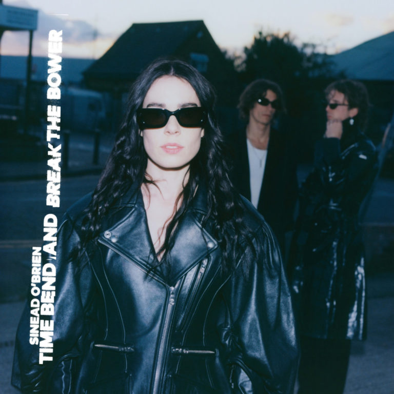 Albumcover zu „TIME BEND AND BREAK THE BOWER“ von Sinead O’Brien, zeigt die Künstlerin in schwarzer Lederjacke und Sonnenbrille frontal zur Kamera blickend, im Hintergrund sind verschwommen zwei weitere Personen zu sehen, die Szenerie wirkt urban und dämmrig.