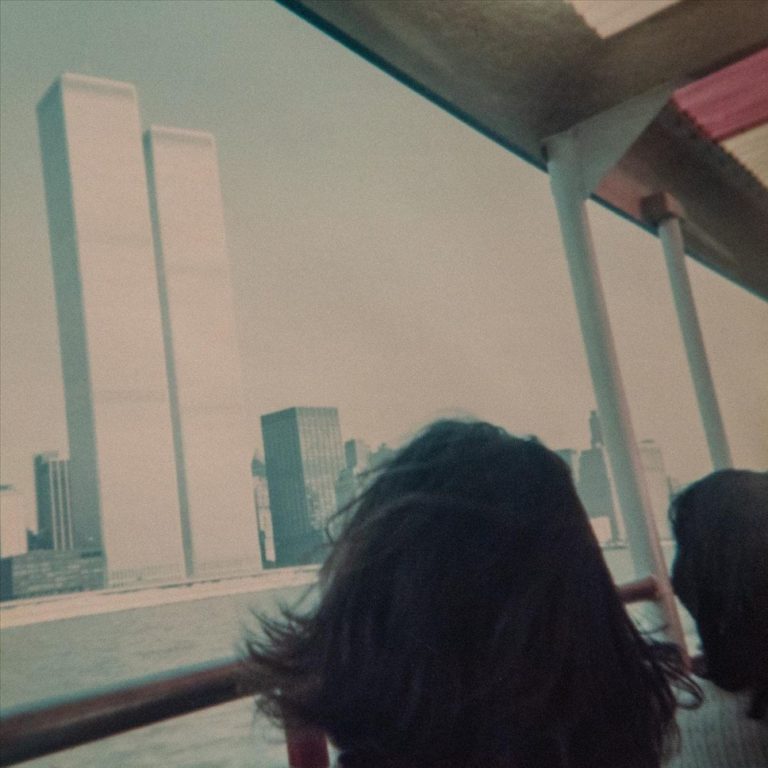 Vintage-angehauchtes Albumcover von Damien Jurados „Reggae Film Star“: Blick aus einem Boot auf die Twin Towers, aufgenommen mit unscharfer Retro-Optik, als wäre man Teil einer Erinnerung aus einem verlorenen Film.