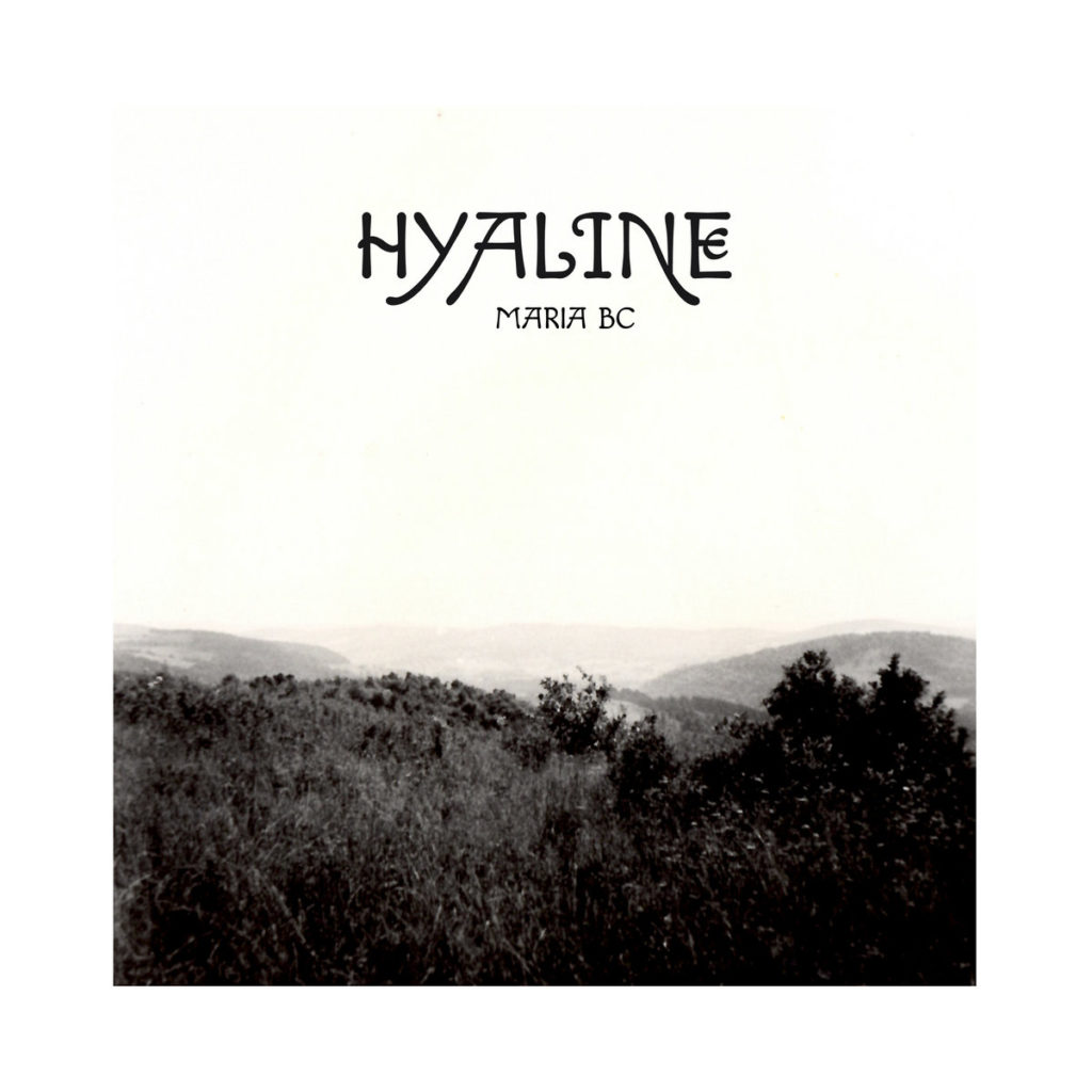 Das Cover zu „Hyaline“ von Maria BC zeigt eine körnige Schwarzweiß-Fotografie einer ruhigen, hügeligen Landschaft. Die Stimmung ist leer, entrückt und introspektiv – ein stilles Echo von Zeit, Raum und Erinnerung.