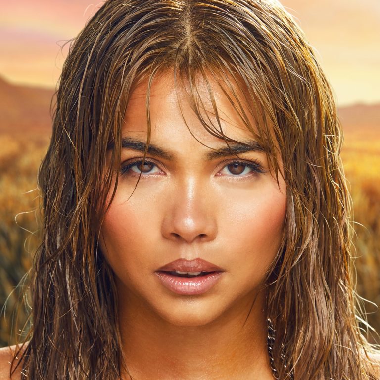 Porträt von Hayley Kiyoko mit nassem Haar, sonnenbeschienenem Gesicht und ernstem Blick, vor goldgetöntem Naturhintergrund – das Cover von „Panorama“.
