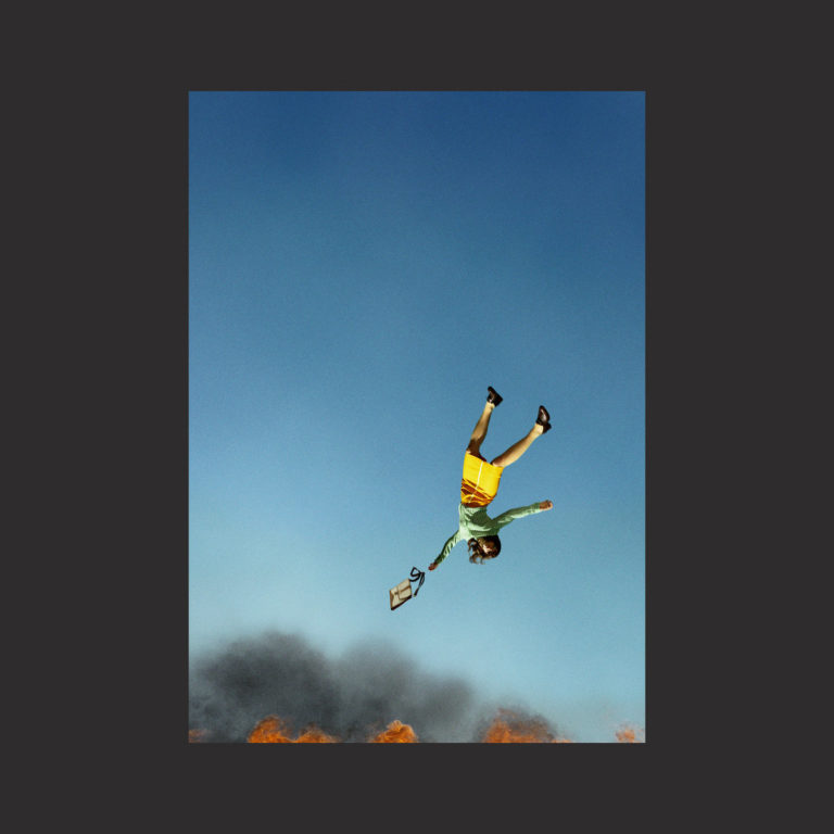 Eine Person in grellbunter Kleidung stürzt kopfüber vom Himmel vor flammendem Horizont – surrealistisches Albumcover zu Cool It Down der Yeah Yeah Yeahs.