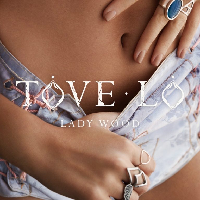 Nahaufnahme eines Bauches mit Händen, die einen Reißverschluss öffnen, Tove Lo Lady Wood Schriftzug