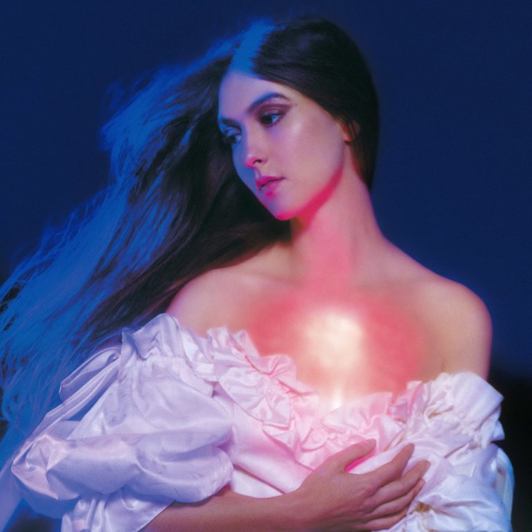 Cover von And in the Darkness, Hearts Aglow: Weyes Blood in einem träumerisch beleuchteten Porträt mit wallendem Haar und einem leuchtenden Licht in der Brust. Die Farbpalette aus tiefem Blau und warmem Magenta erzeugt eine sakral-futuristische Aura – zwischen Verwundbarkeit und Erleuchtung.