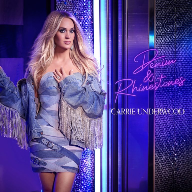 „Carrie Underwood strahlt in einem coolen Denim-Outfit mit funkelnden Fransen vor einer leuchtenden blauen Kulisse – Denim & Rhinestones vereinen Country-Pop-Glanz und Spaß.“