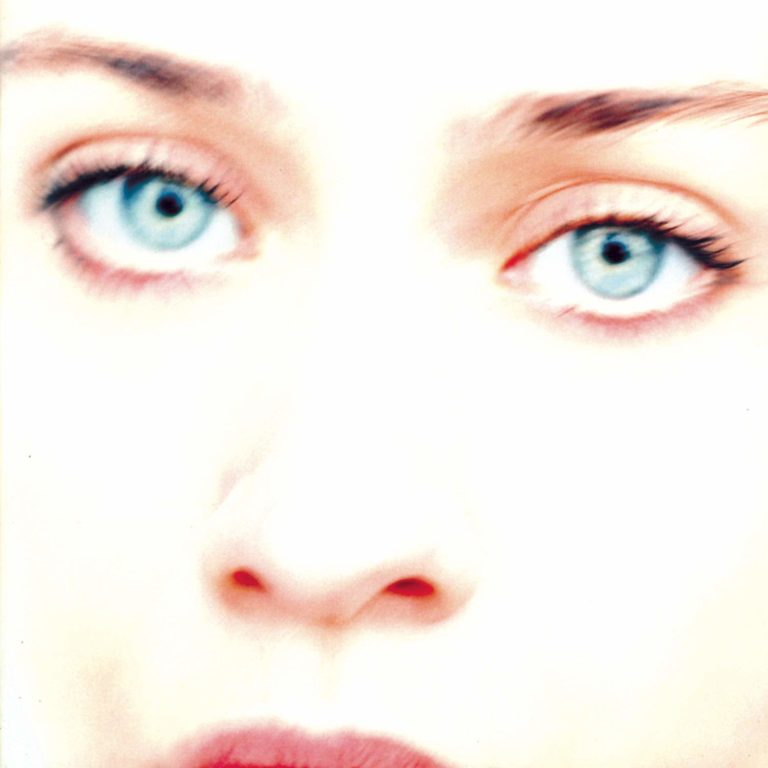 Nahaufnahme eines Gesichts mit Fokus auf blauen Augen und hellem Hintergrund.