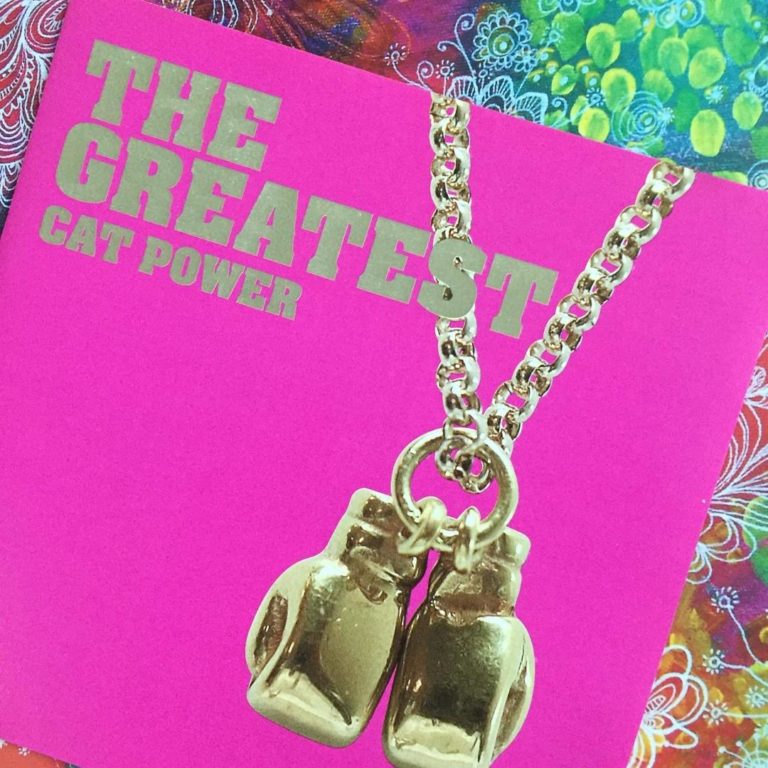Pinkes Albumcover mit goldener Kette und Boxhandschuh-Anhänger.