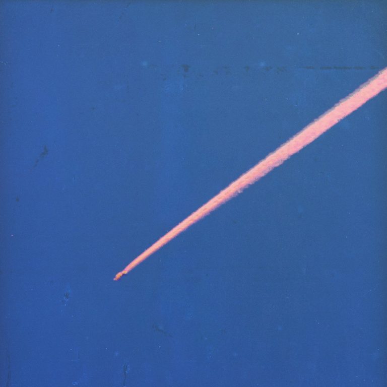 Ein pinker Kondensstreifen zieht sich diagonal über einen tiefblauen Himmel.