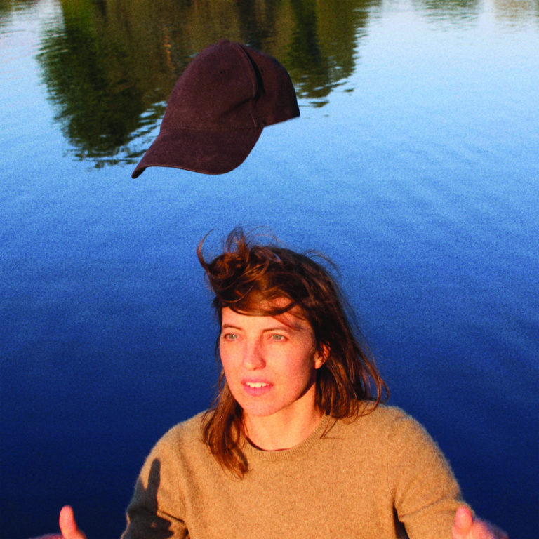 Cover des Albums „Prize“ von Rozi Plain mit einer Frau vor ruhigem Wasser, über ihr schwebt eine schwarze Baseballkappe – poetisch, verspielt, introspektiv.