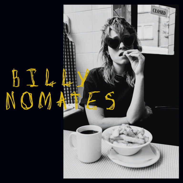 Frau mit Sonnenbrille sitzt in einem Café, isst Pommes, trinkt Kaffee