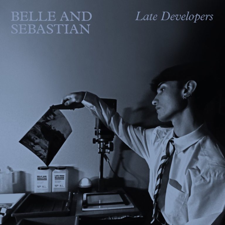 Cover des Albums „Late Developers“ von Belle and Sebastian zeigt eine Person im Fotolabor beim Entwickeln eines Fotos – nostalgisch, künstlerisch, blau getönt.