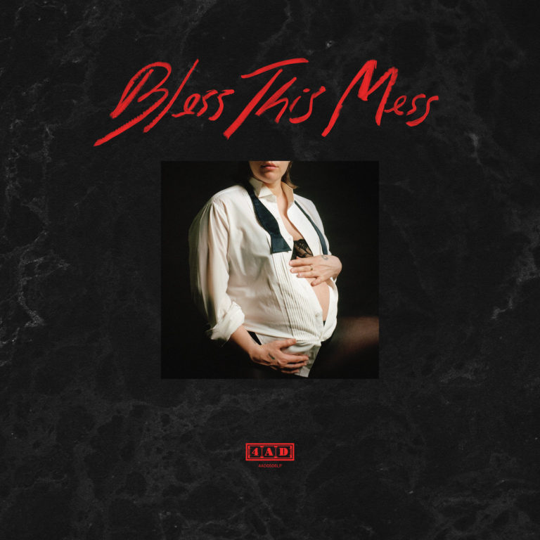 Albumcover von „Bless This Mess“ von U.S. Girls: Eine schwangere Person im offenen Hemd vor schwarzem Hintergrund, mit rotem Schriftzug über dem Bild.