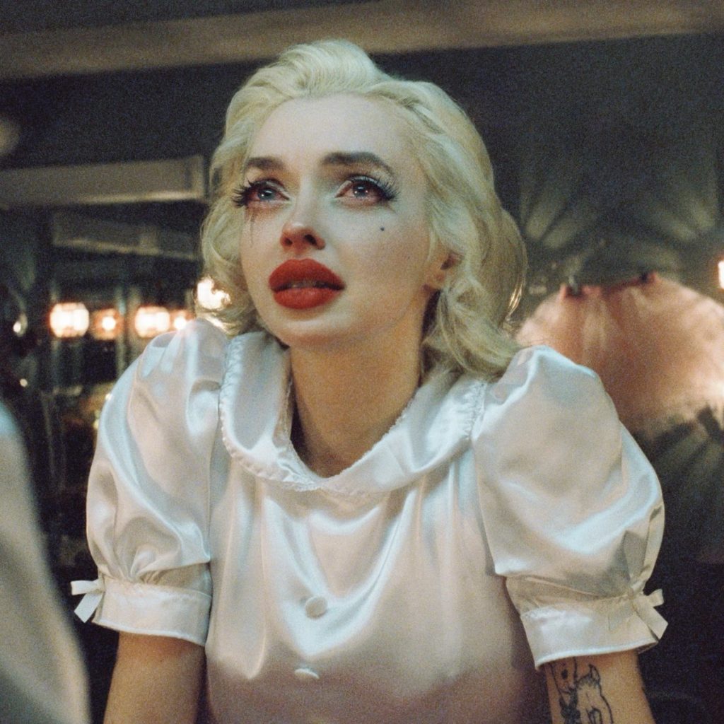 Cover des Albums „Main Character“ von Glüme mit der Künstlerin im Retro-Monroe-Look, in Tränen aufgelöst, mit weißem Kleid und Vintage-Schminktisch im Hintergrund.