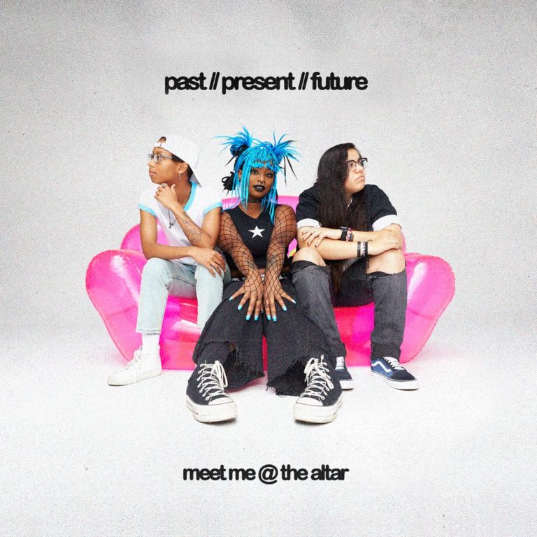 Cover von „Past // Present // Future“ mit der Band Meet Me @ The Altar auf pinkem Sofa – drei Mitglieder mit auffälligem Styling vor weißem Hintergrund.